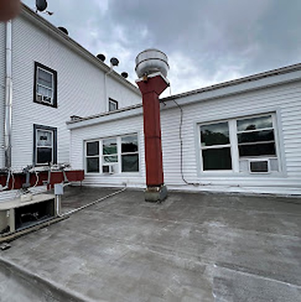 Commercial flat roof with brick chimney and white siding